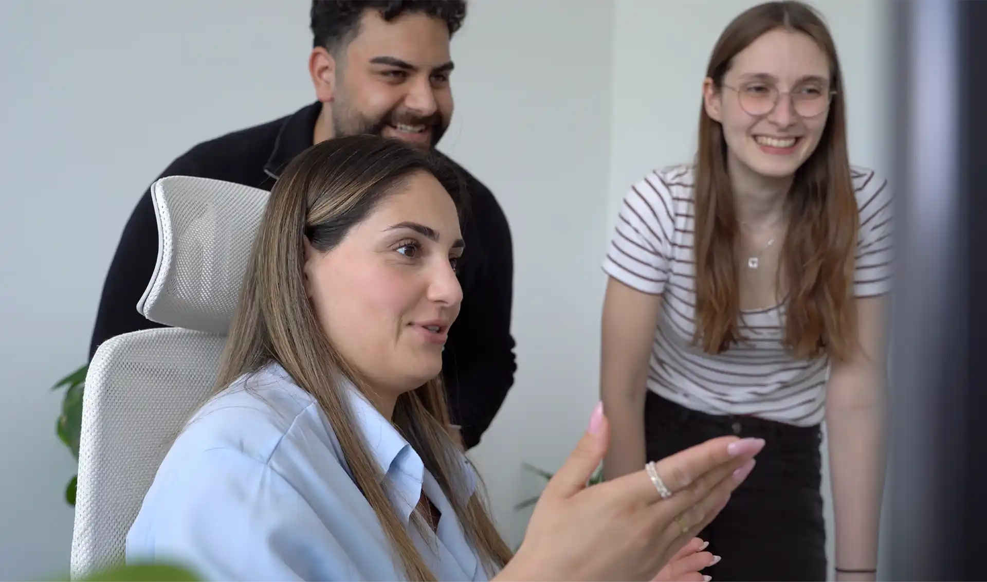 Die Mitarbeiter Juan und Alicia lassen sich am PC etwas von der Mitarbeiterin Larissa erklären