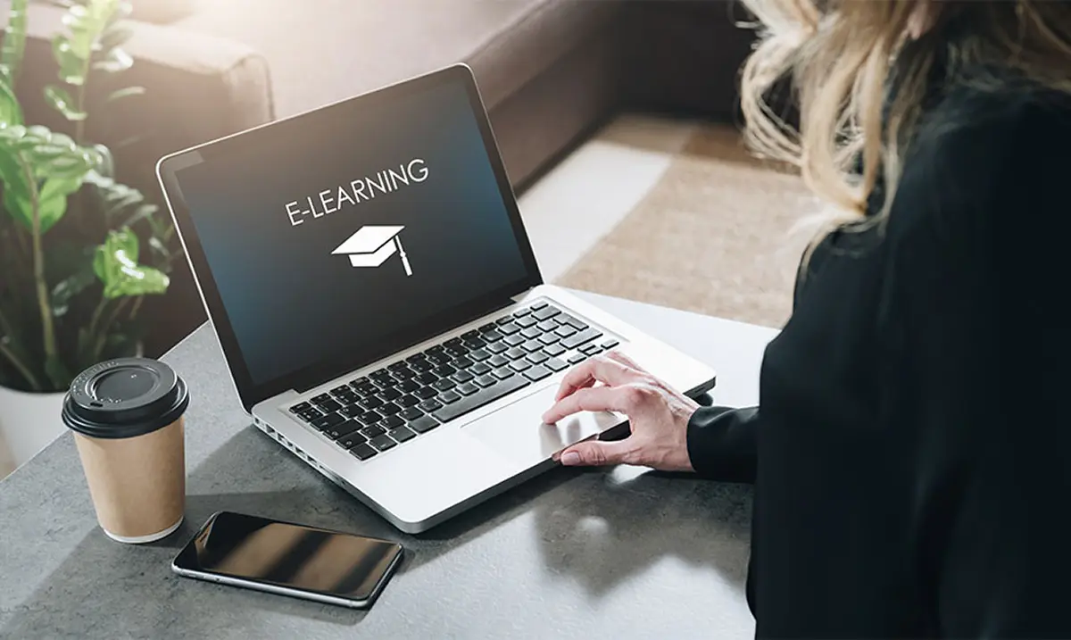 Frau vor Laptop mit E-Learning-Symbol auf Bildschirm im Format 920x550