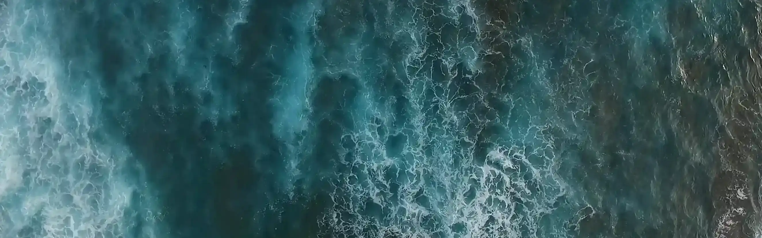 Das Bild zeigt Wellen, die auf einen Strand zulaufen.