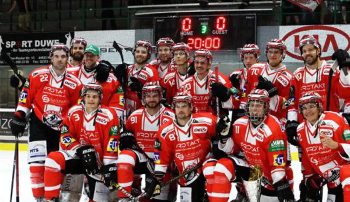 Eine Eishockeymannschaft posiert mit ihrer Ausrüstung auf dem Eisfeld für ein Foto