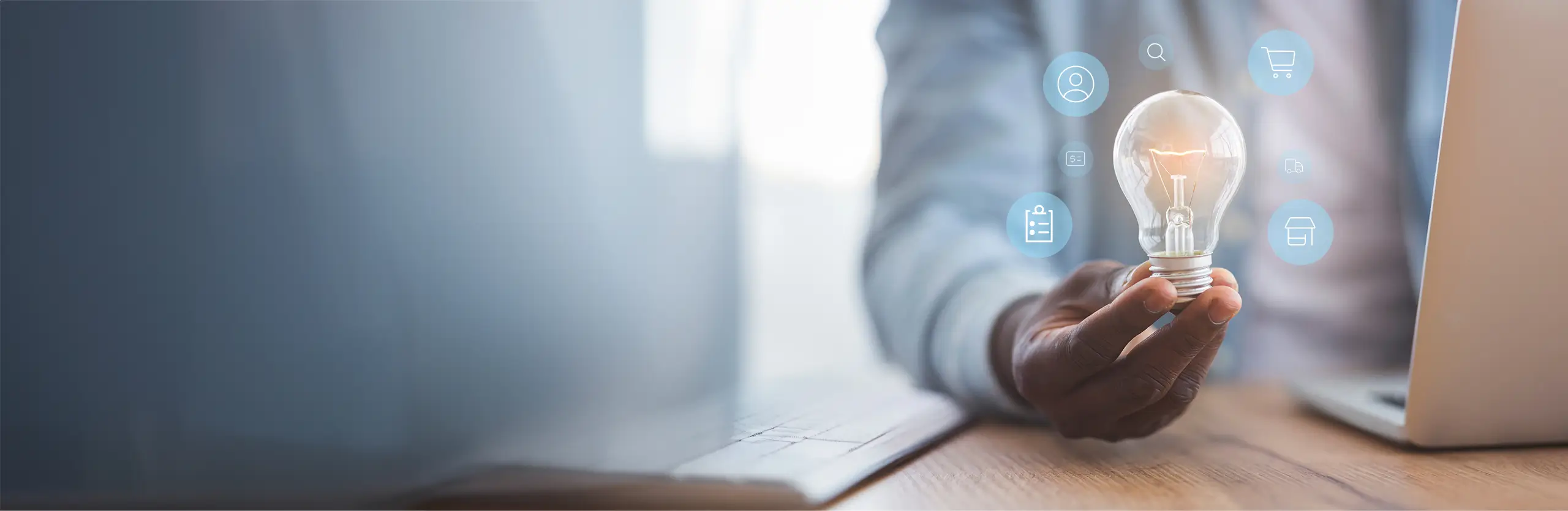 Person hält eine Glühbirne mit digitalen Symbolen rundherum – steht für innovative Ideen und technologische Integration im Unternehmen