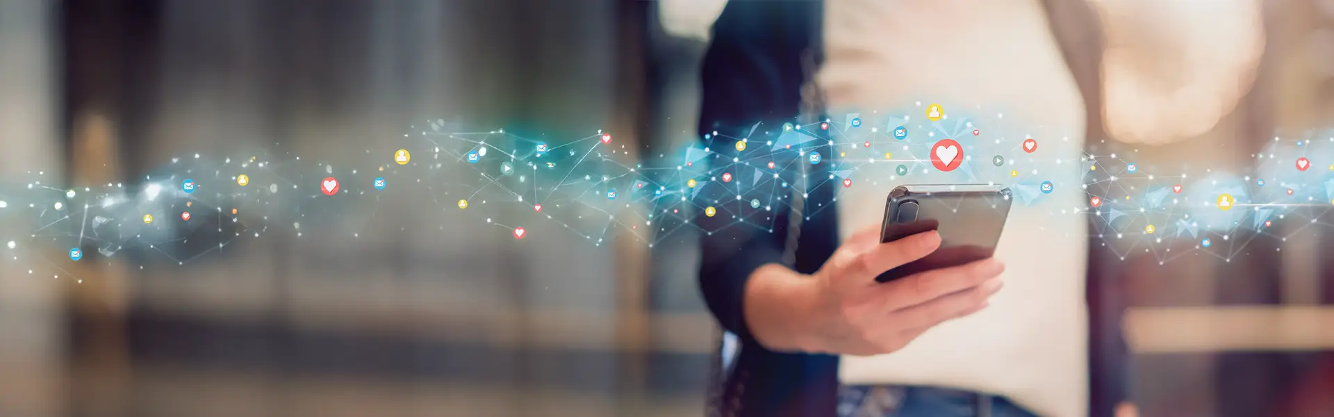 Person hält ein Smartphone, über dem digitale Symbole für soziale Medien und Netzwerke schweben – symbolisiert digitale Kommunikation und Social Media Interaktion.
