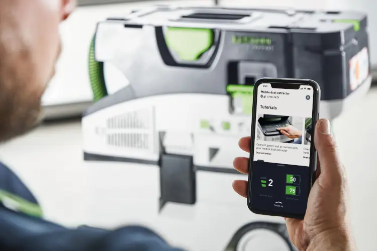 Ein Mann hält ein Smartphone in seiner rechten Hand und schaut sich Tutorials von der Festool GmbH an.