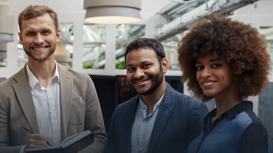 Geschäftstreffen in modernem Büro – drei Personen im Gespräch, eine Person mit Notizbuch.