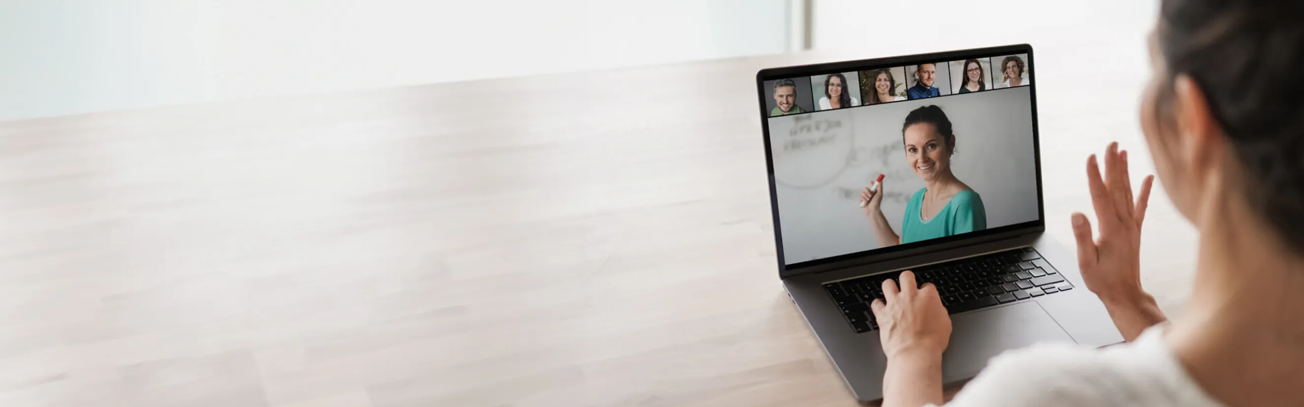 Frau nimmt an einer Videokonferenz über ihren Laptop teil und kommuniziert mit anderen Teilnehmern.