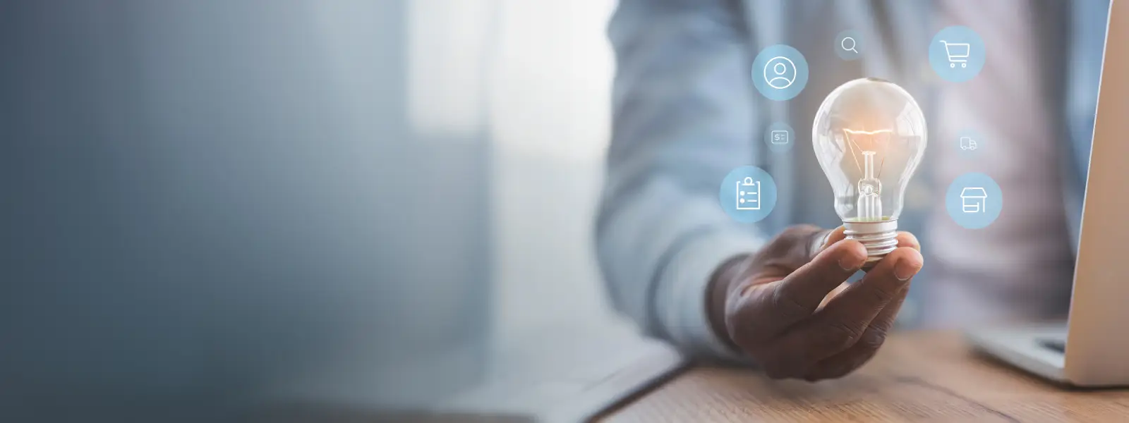 Person hält eine Glühbirne mit digitalen Symbolen rundherum – steht für innovative Ideen und technologische Integration im Unternehmen