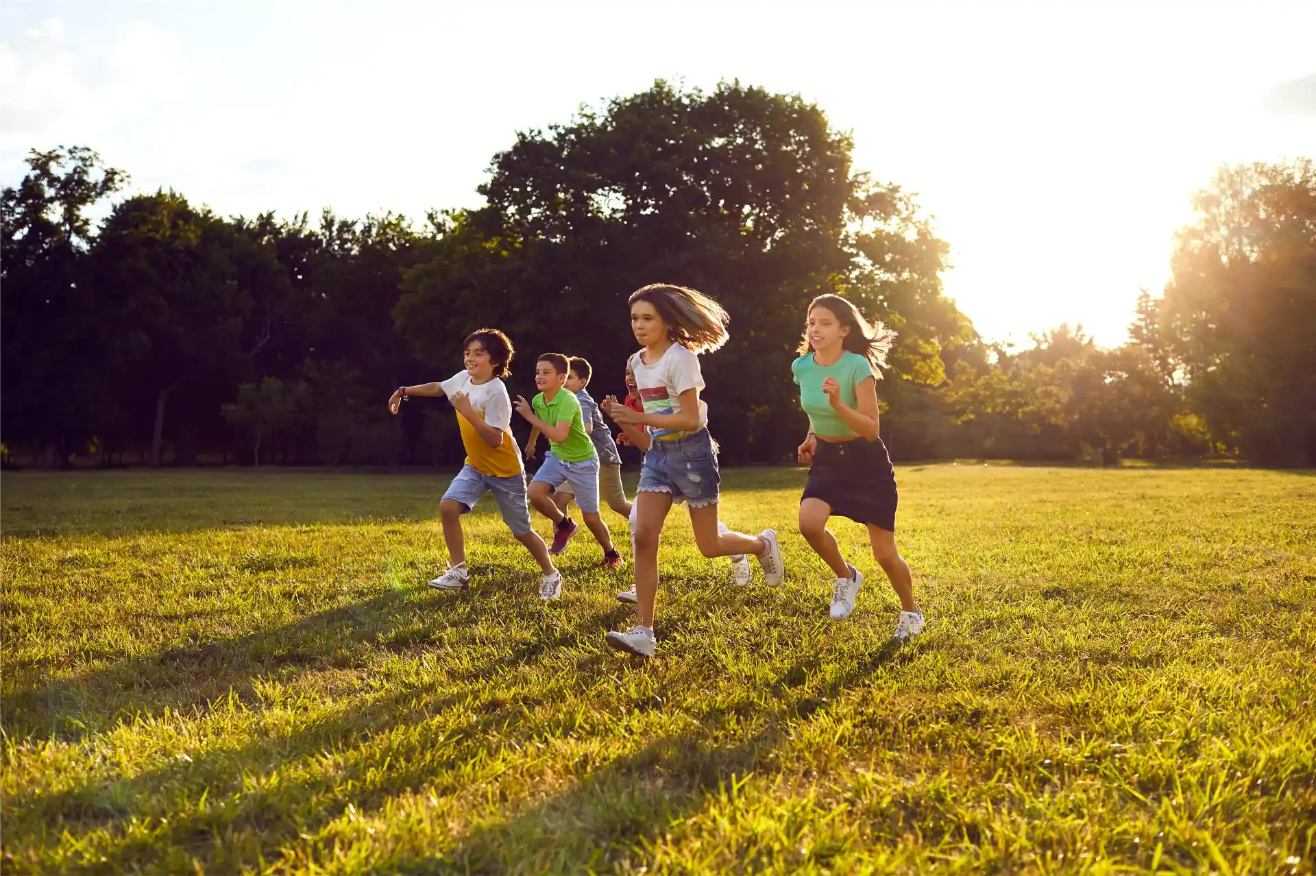 Mehrere Kinder laufen spielend über eine Wiese.